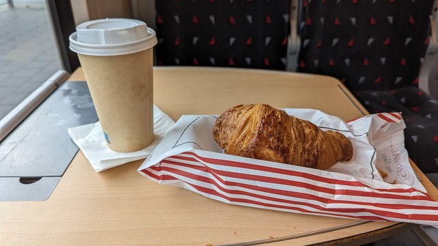 Croissant und Kaffee auf einem Tisch im Zug 